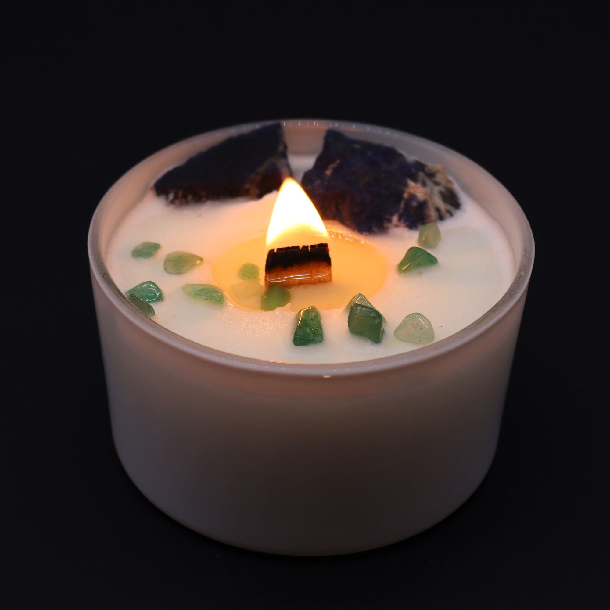 Candle with green stones on a black background