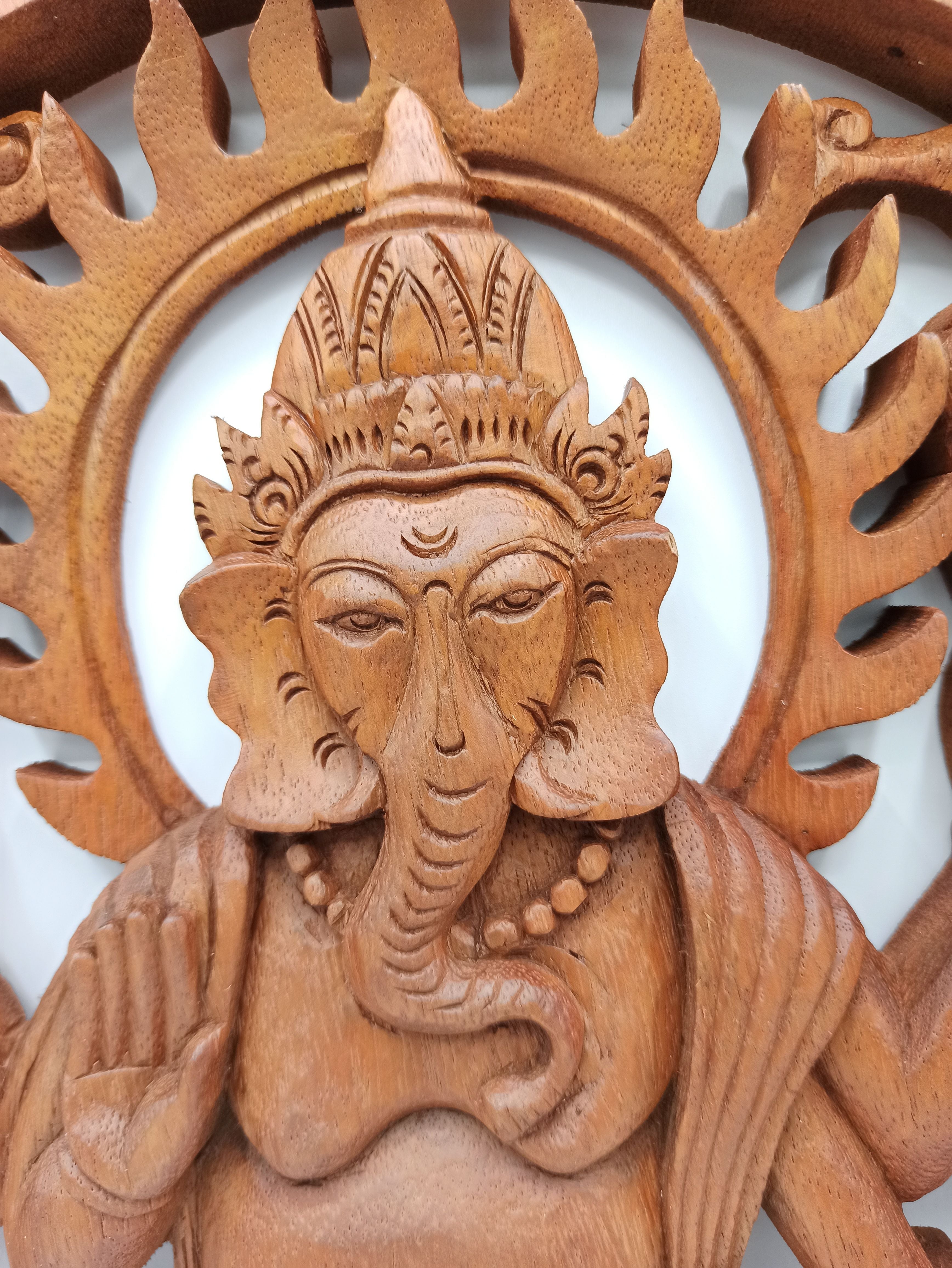Wooden sculpture of a deity with intricate carvings on a white background