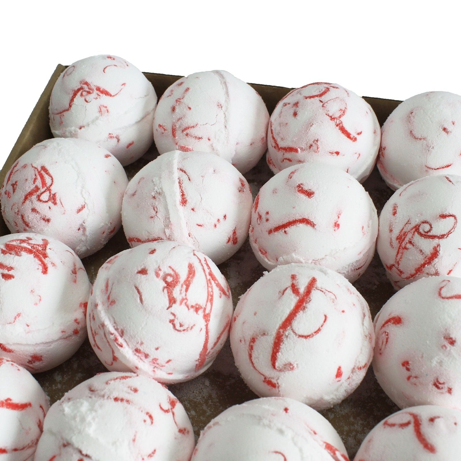 White bath bombs with red swirls in a cardboard box