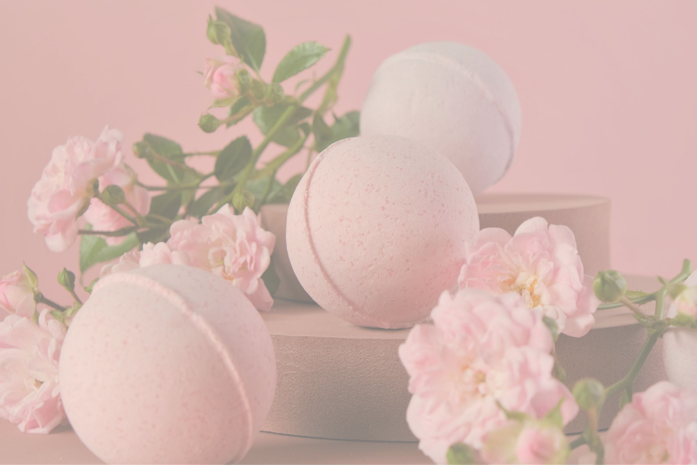 Pink bath bombs with soft flowers creating a relaxing self-care atmosphere.