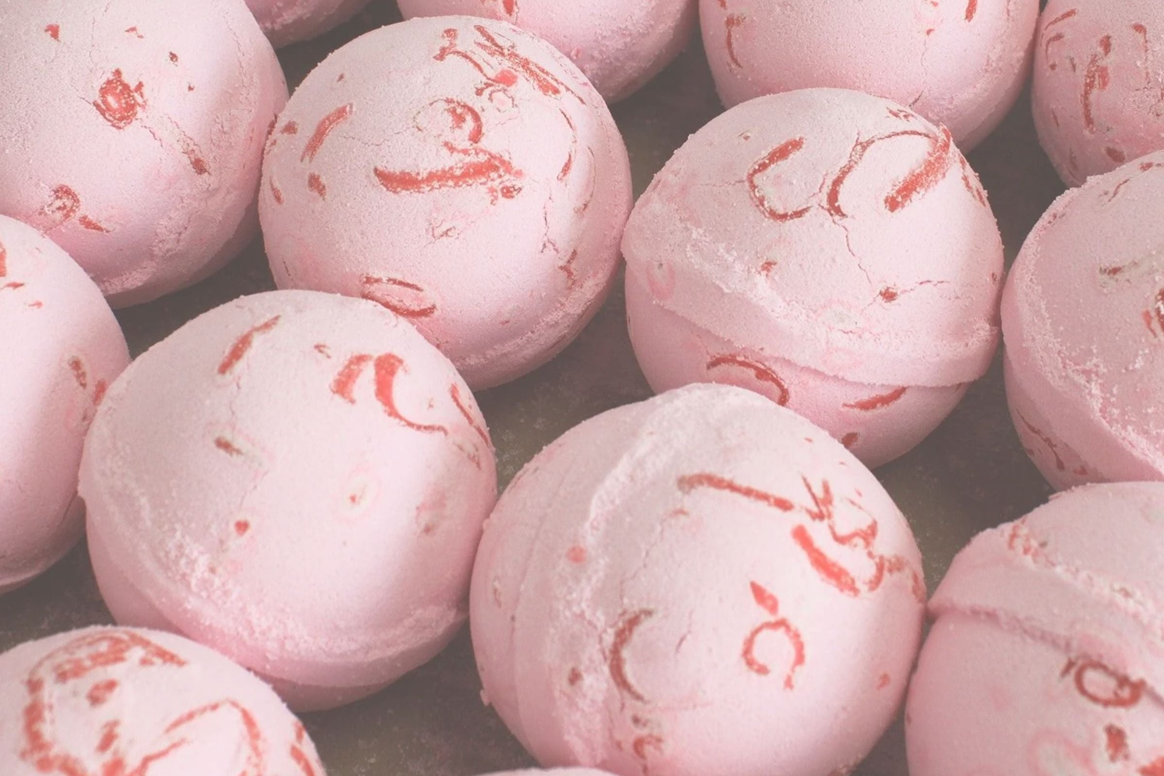 Close-up of pink bath bombs with red swirl patterns on a dark background