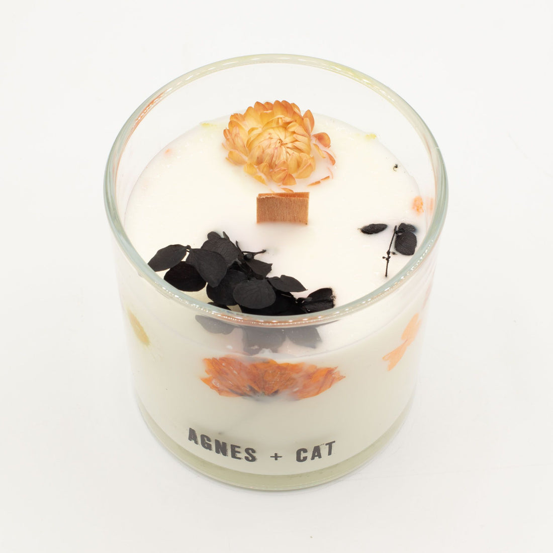 Decorative candle with flowers and leaves in a glass container on a white background