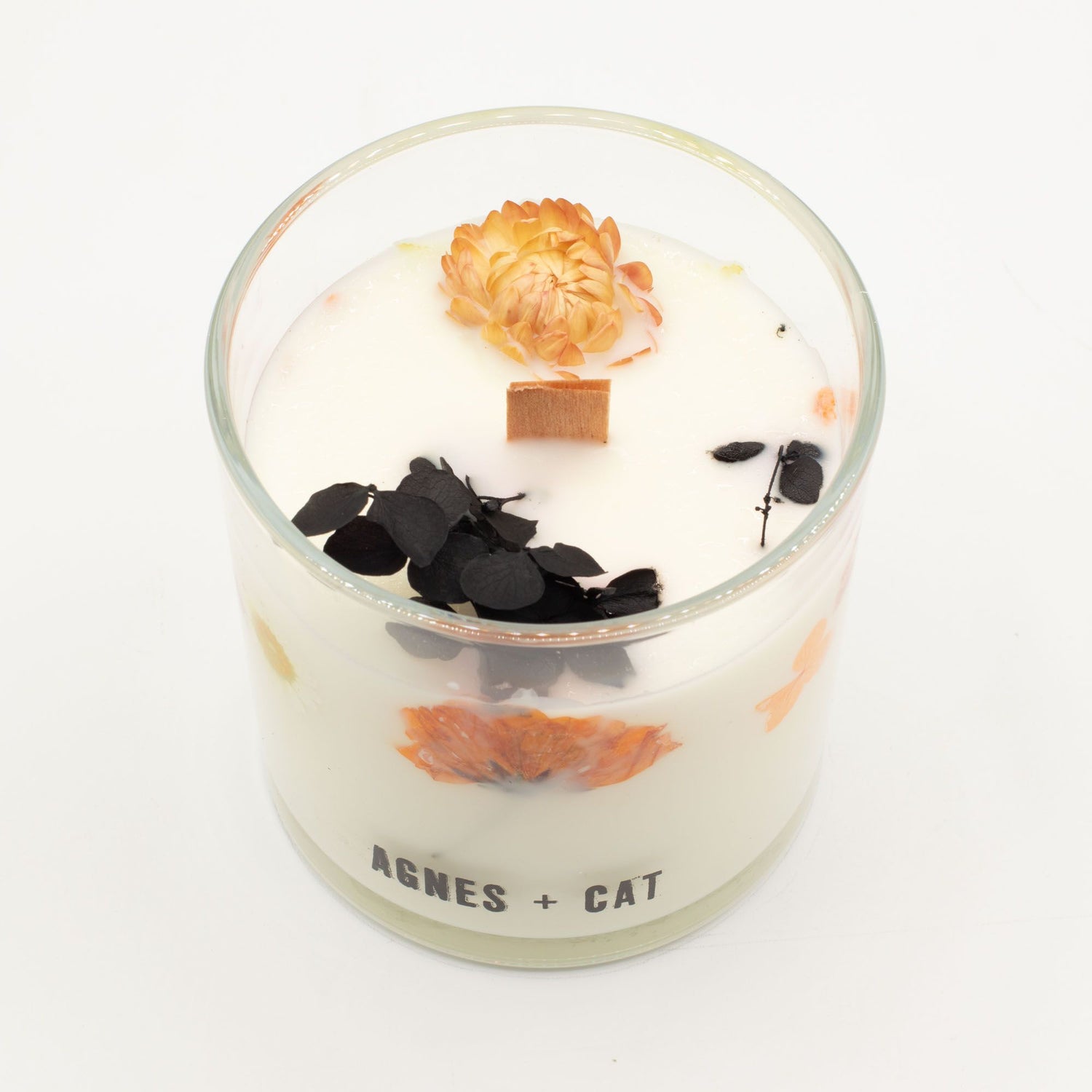 Decorative candle with flowers and leaves in a glass container on a white background