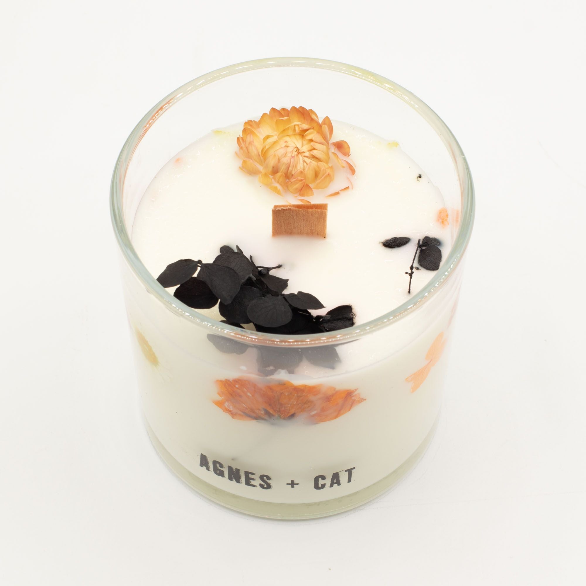 Decorative candle with flowers and leaves in a glass container on a white background