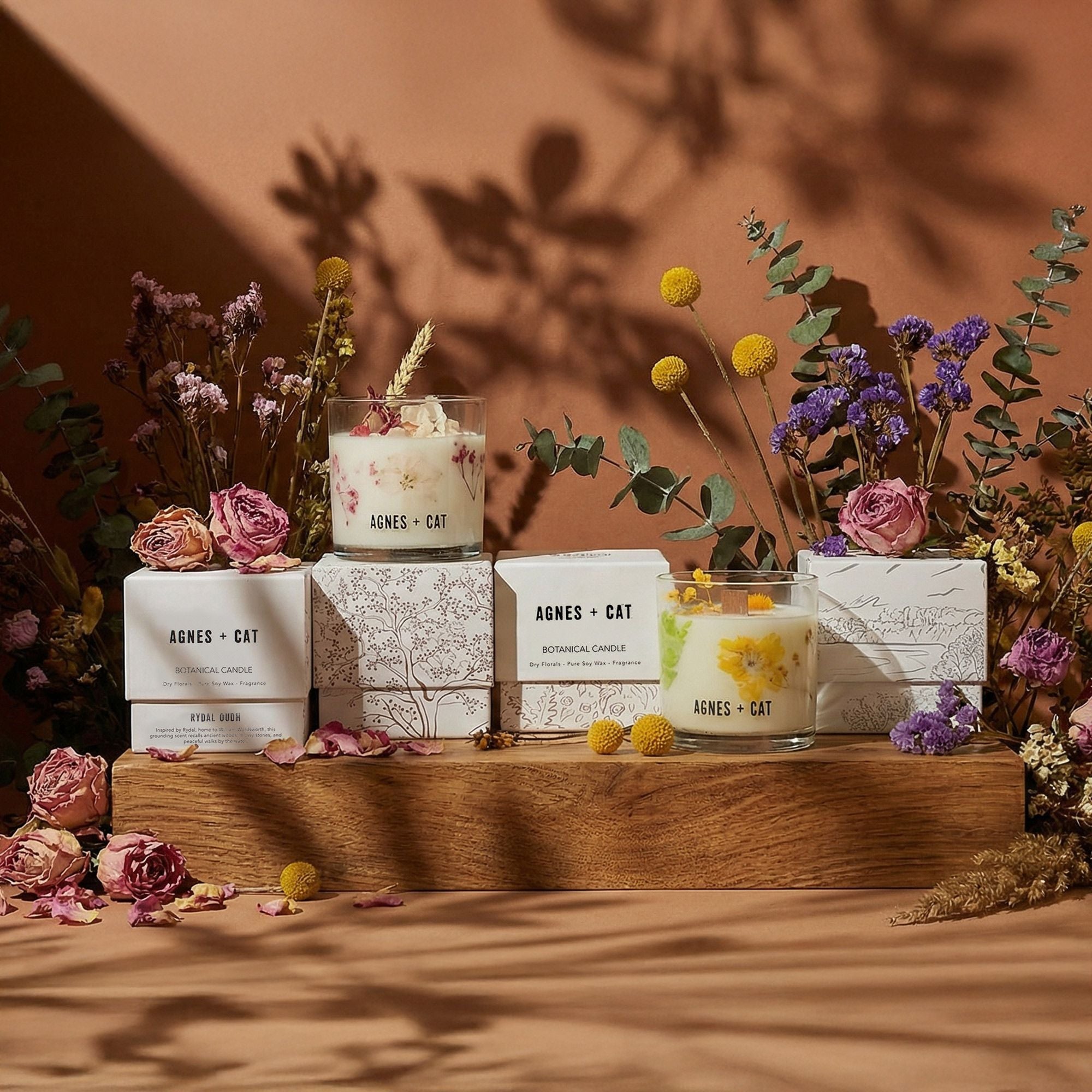 Candles with floral packaging on a wooden stand against a warm brown background