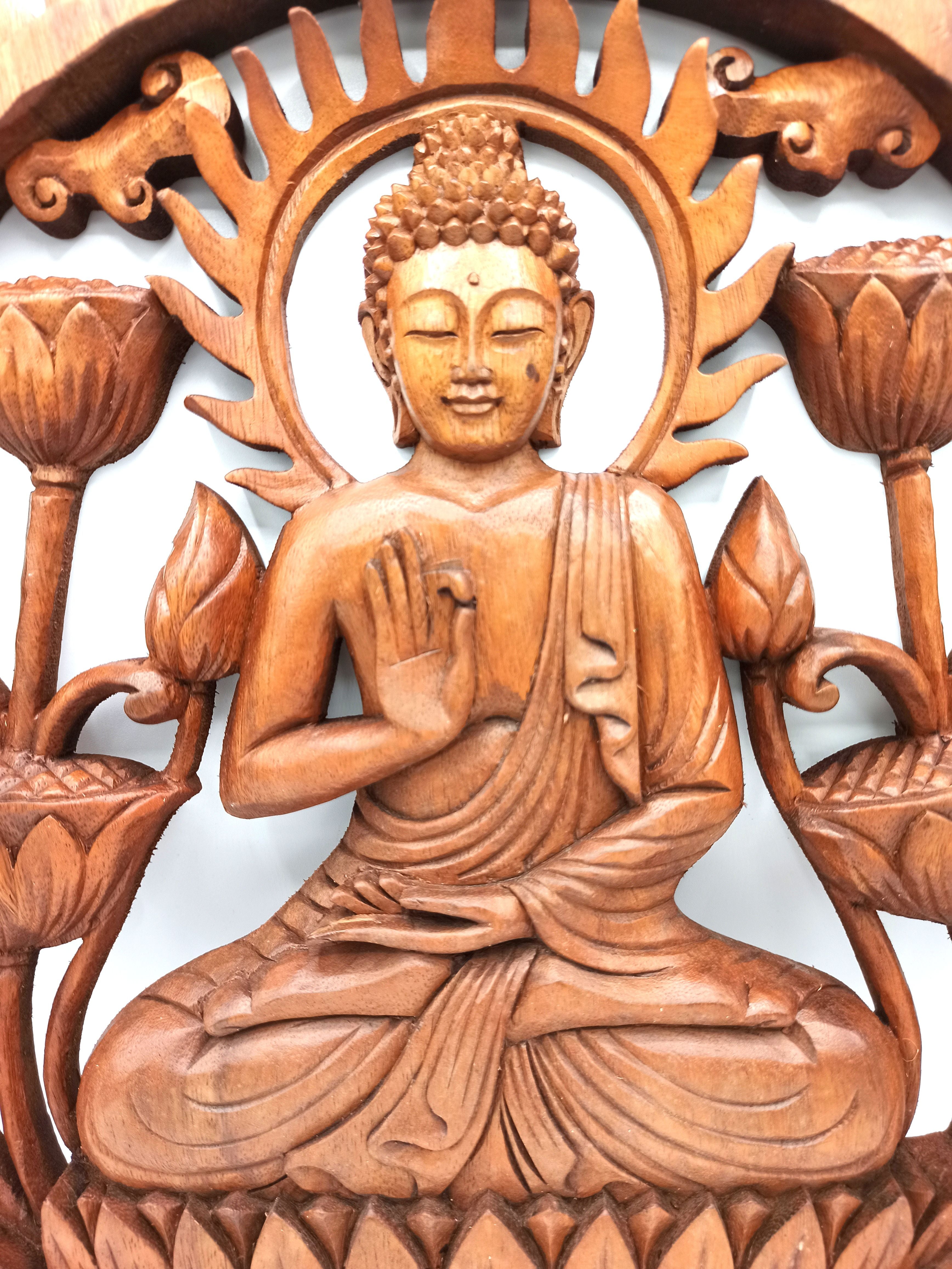 Wooden carving of a seated Buddha figure with lotus flowers on a white background