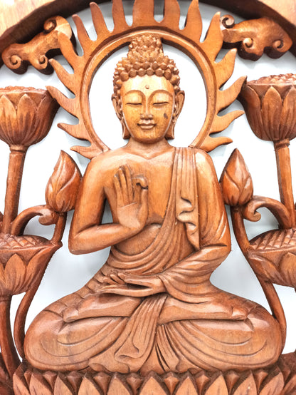 Wooden carving of a seated Buddha figure with lotus flowers on a white background