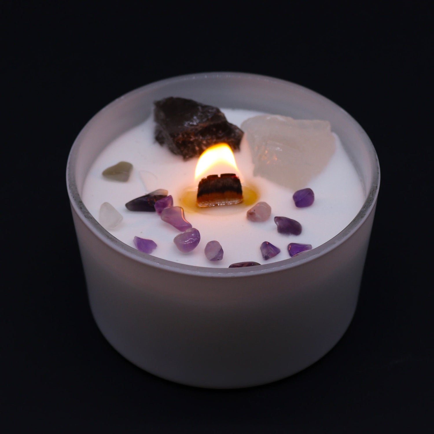 Candle with embedded stones on a black background