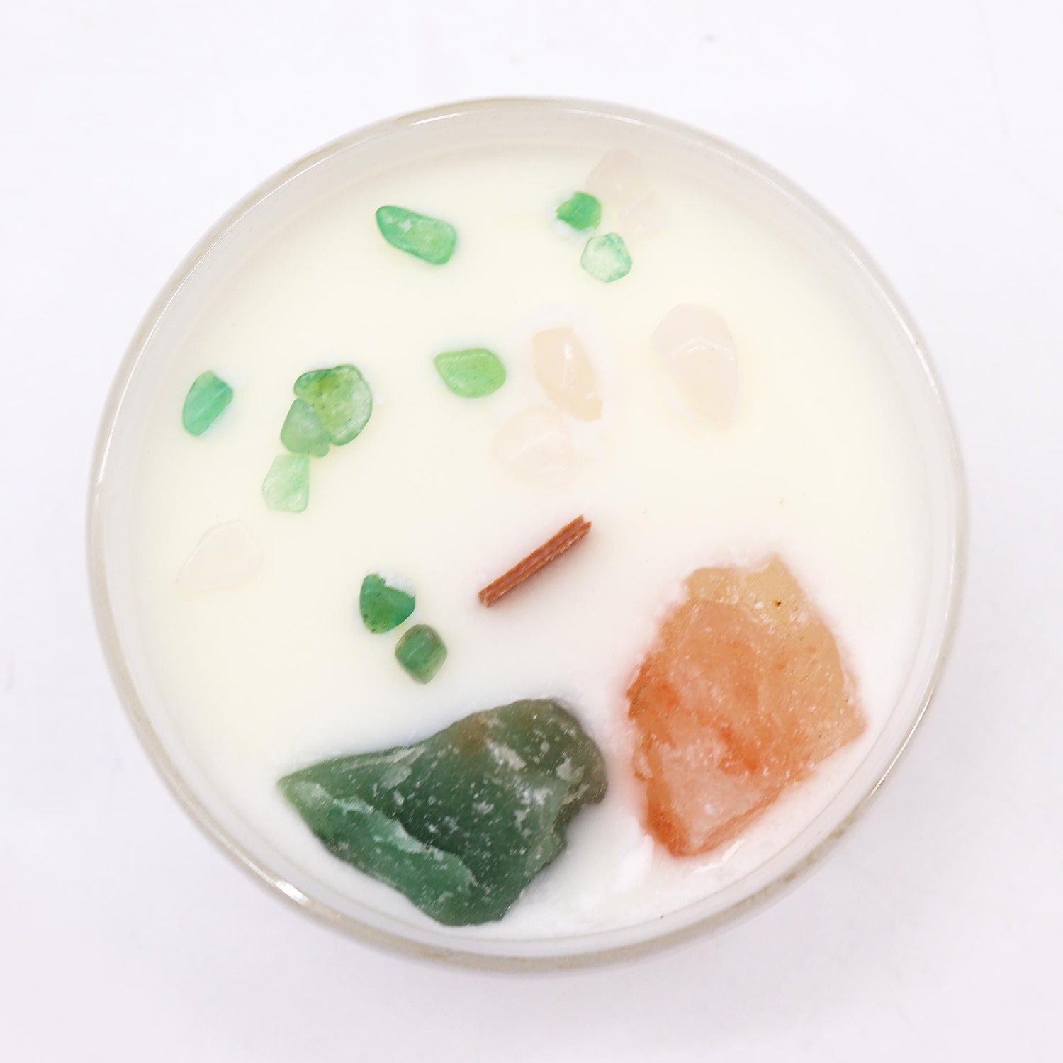 Round candle with green and orange elements on a white background