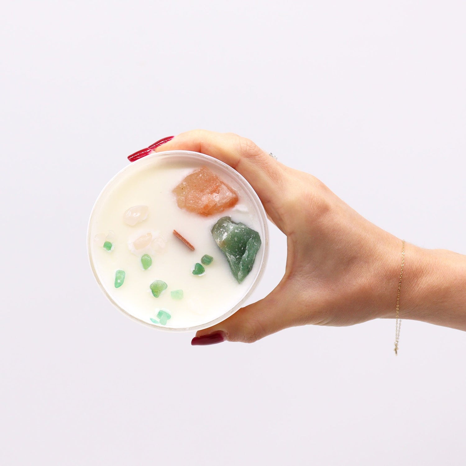 Hand holding a bowl of dessert with fruits against a white background