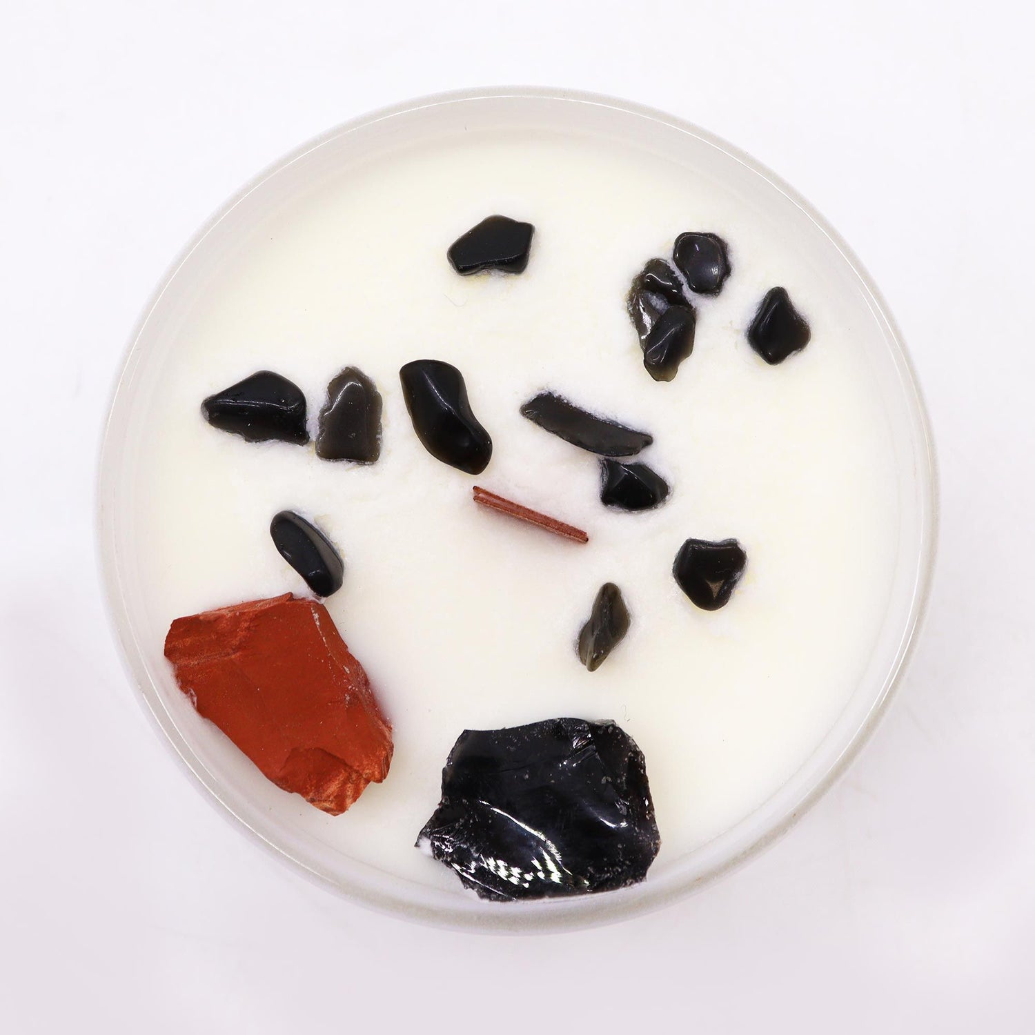 Round white candle with black and red elements on a white background