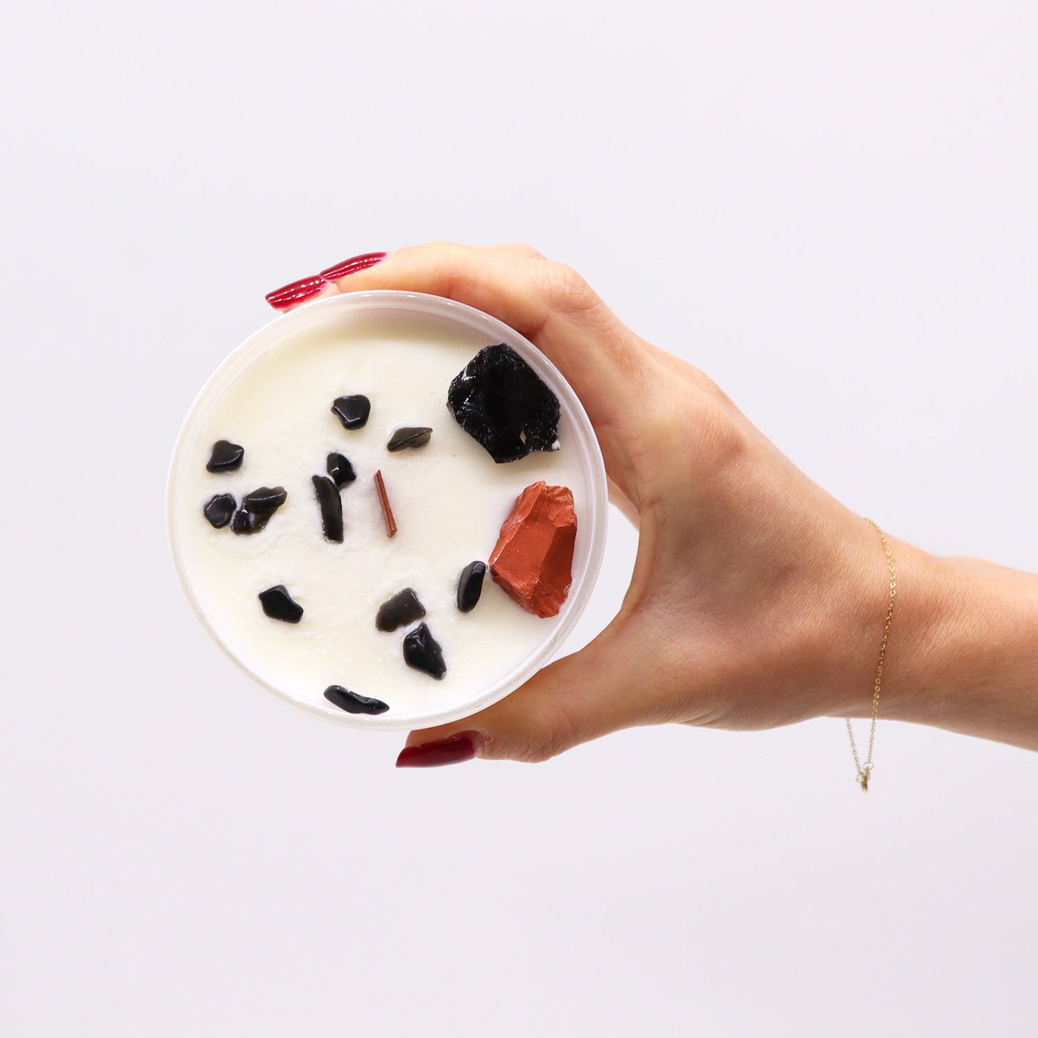 Hand holding a bowl of yogurt with fruits and granola on a white background