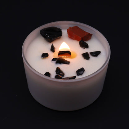 Candle with dark pieces on top against a black background