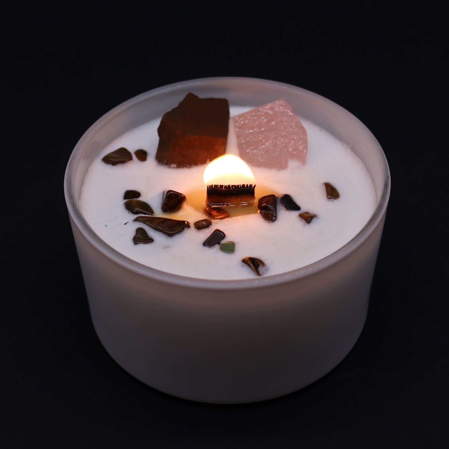 Candle with decorative stones on a black background