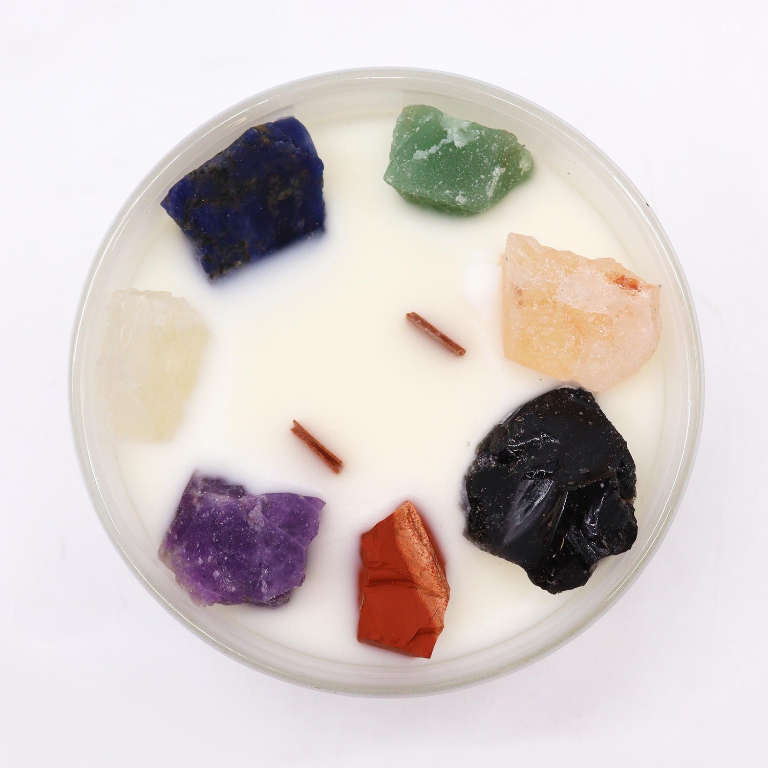 Candle with embedded colorful stones on a white background