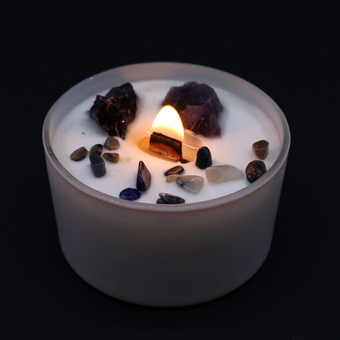 Candle with embedded stones on a black background