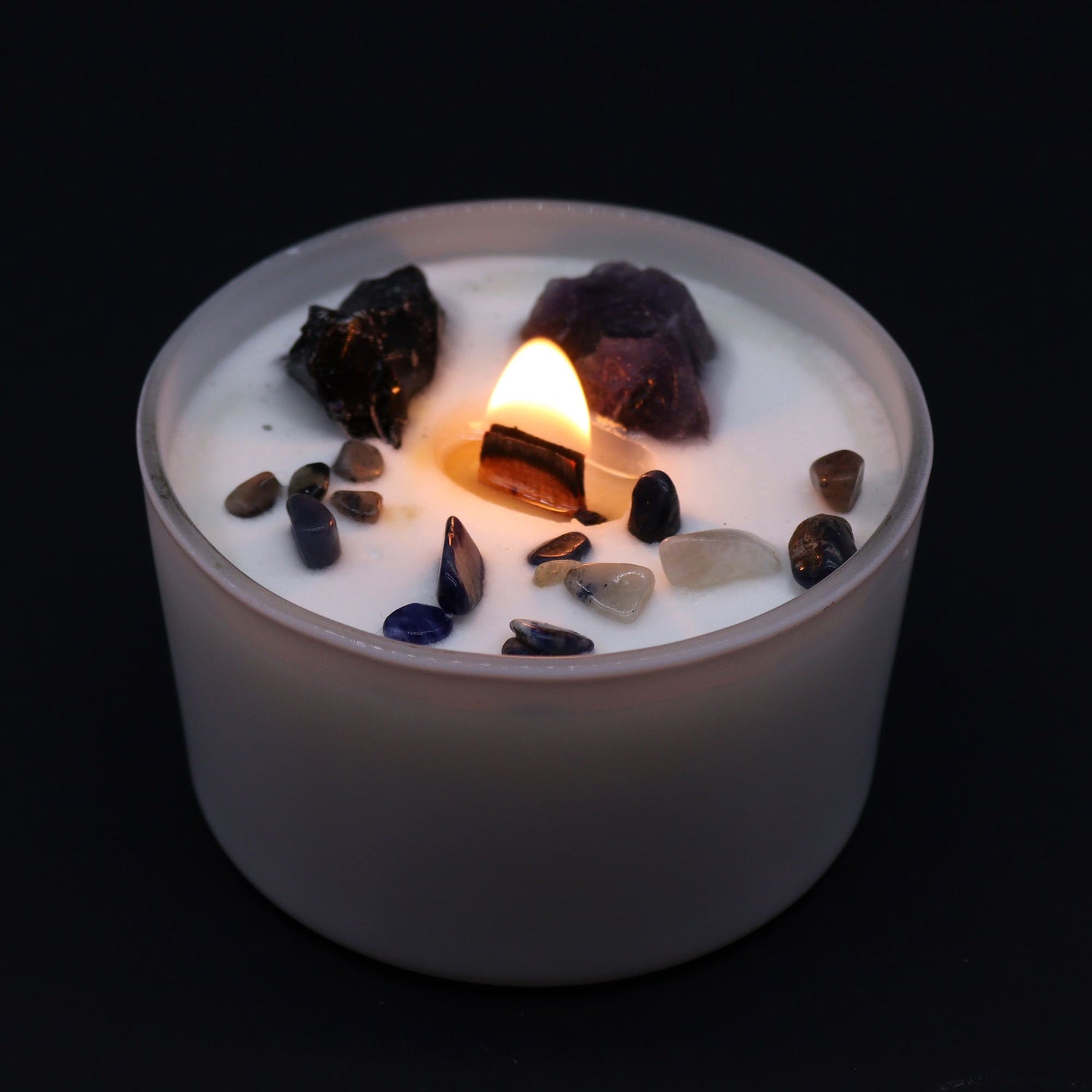 Candle with embedded stones on a black background
