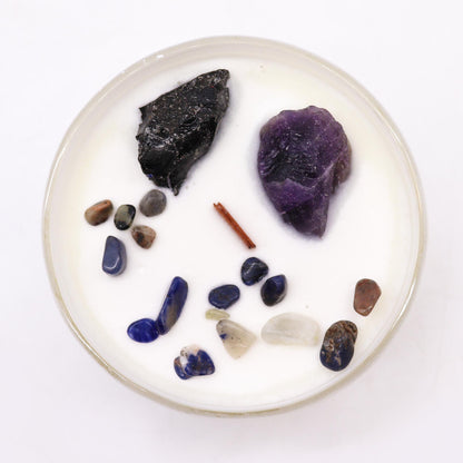 Round white candle with assorted stones and a stick on a white background