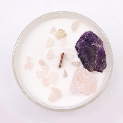Candle with natural stones and a purple crystal on a white background
