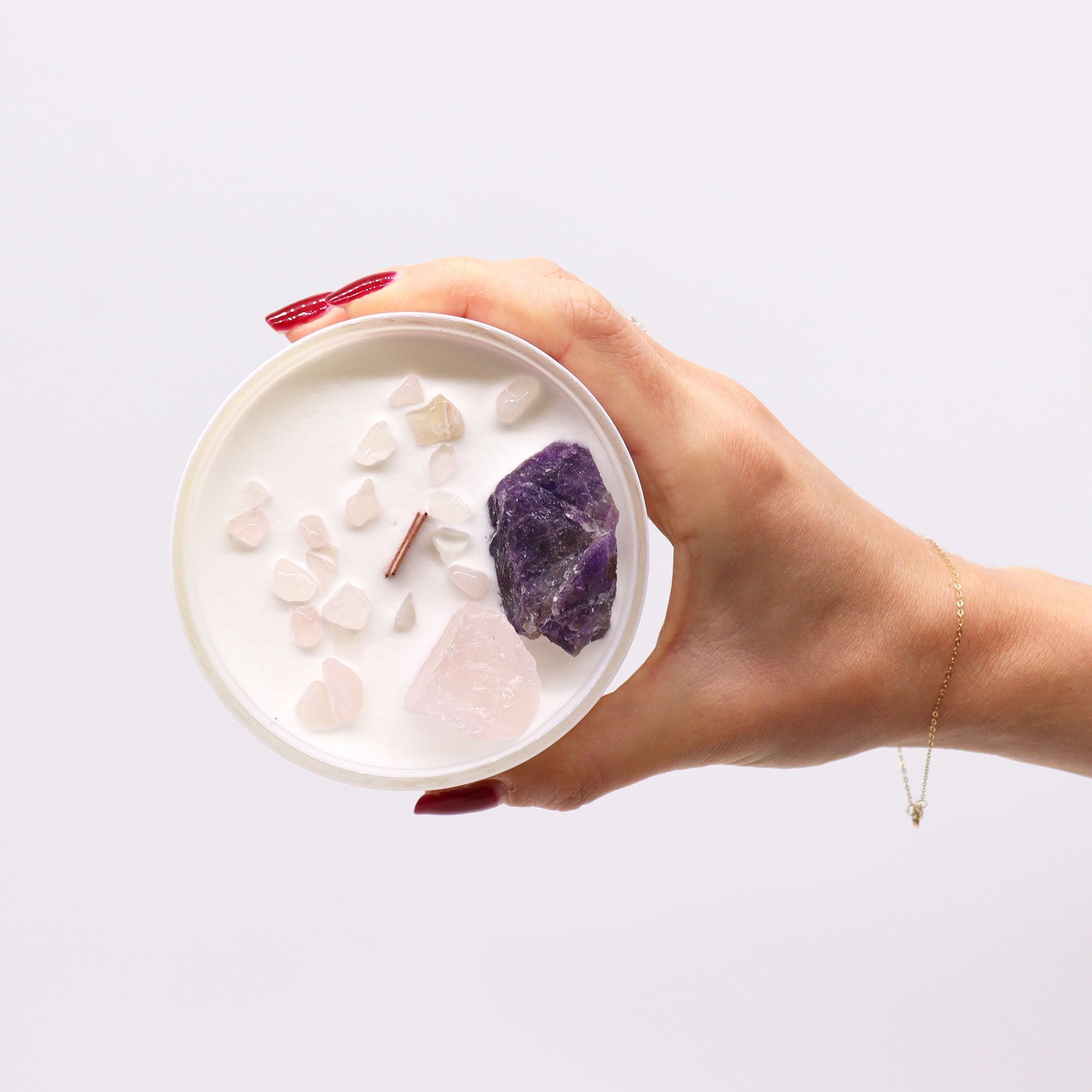 Hand holding a container with crystals on a white background