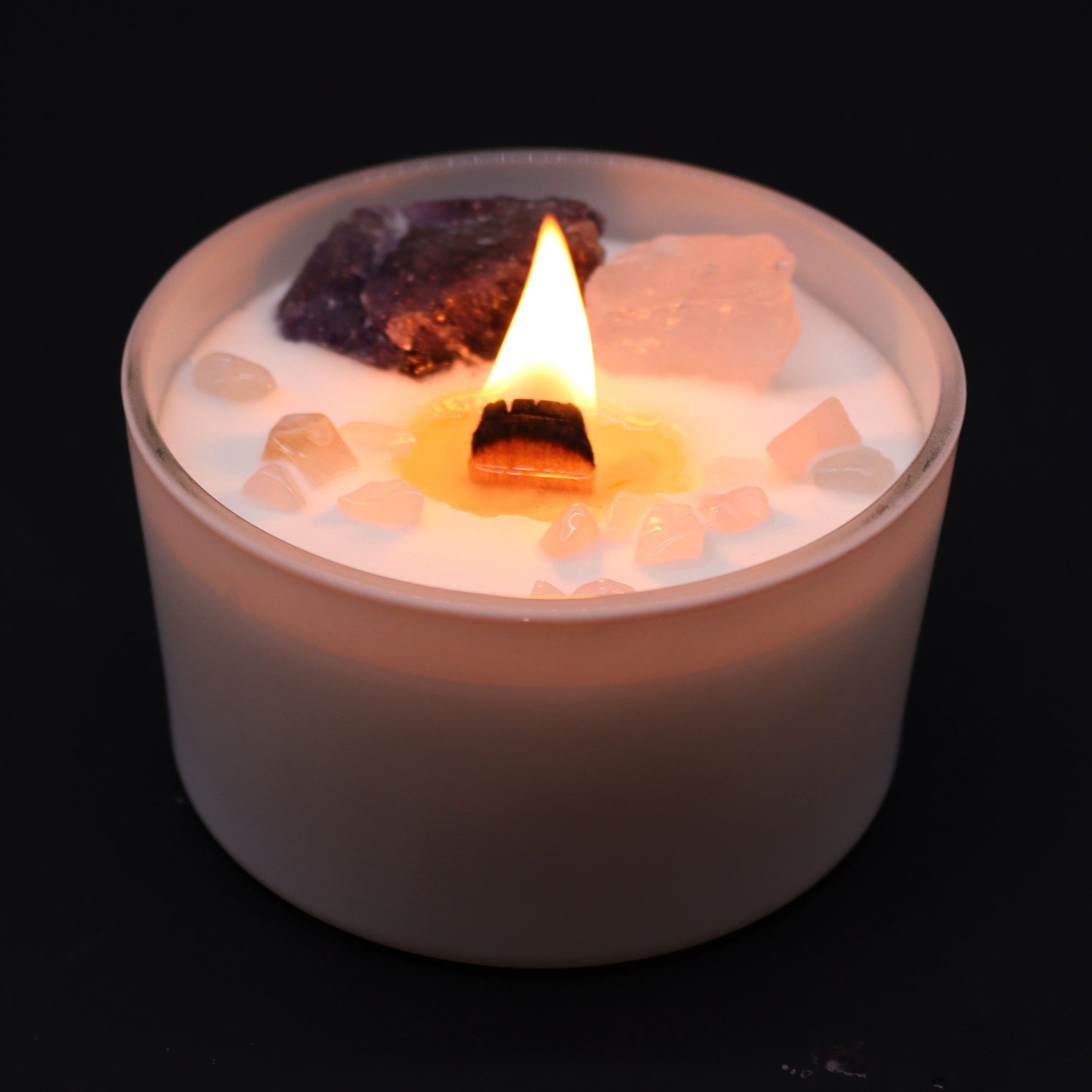 Candle with rocks and pebbles in a container on a black background