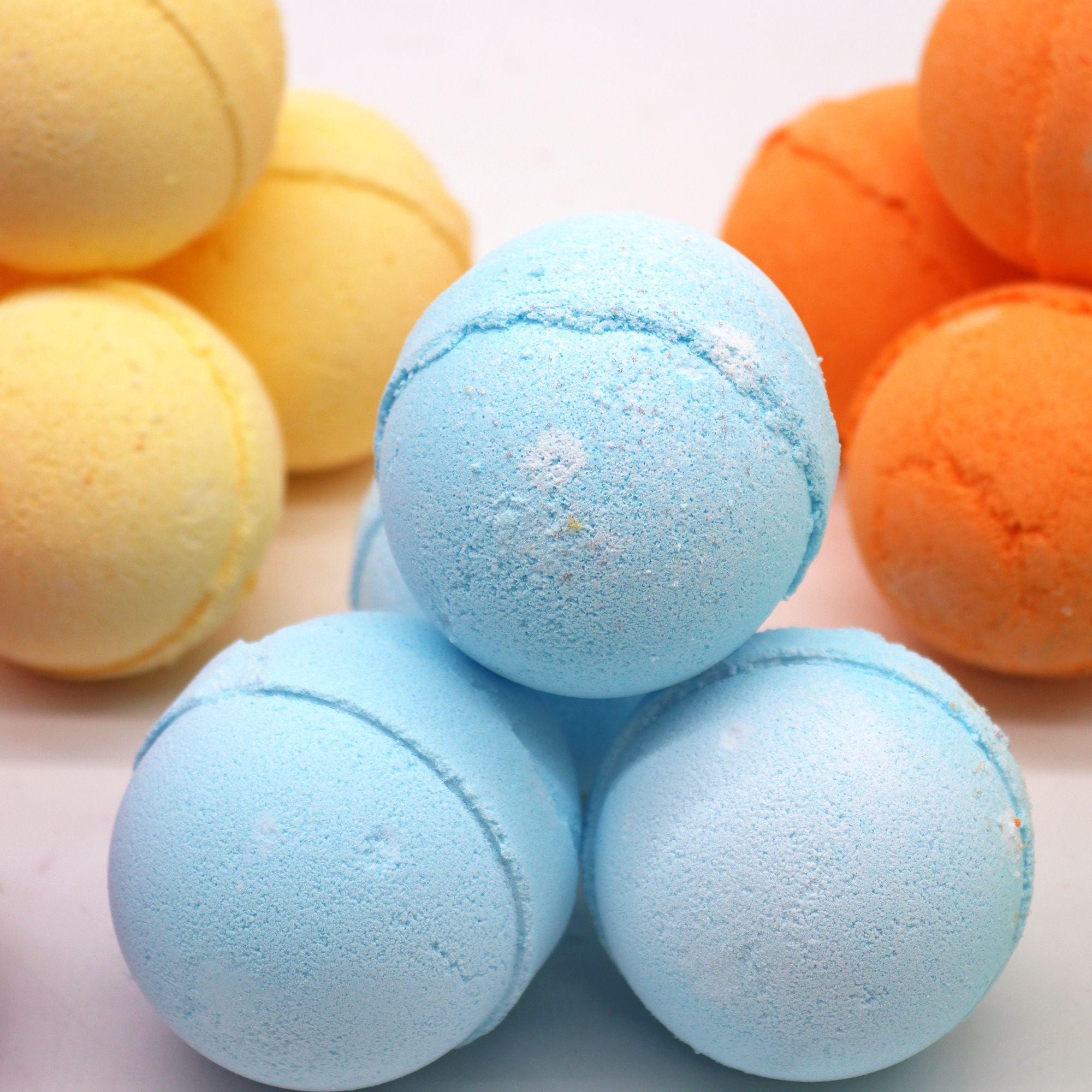 Bath bombs in blue, yellow, and orange on a light background
