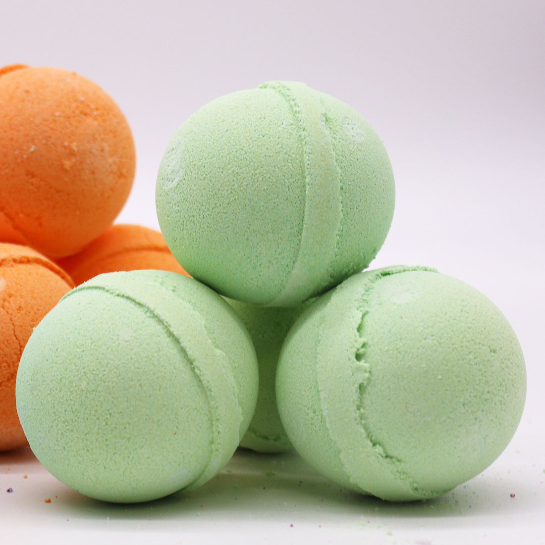 Green and orange bath bombs on a white background