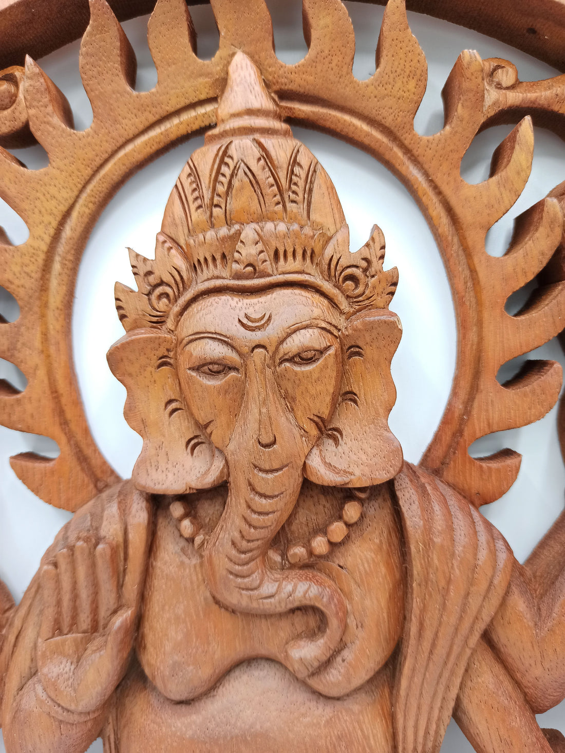 Wooden sculpture of a deity with intricate carvings on a white background
