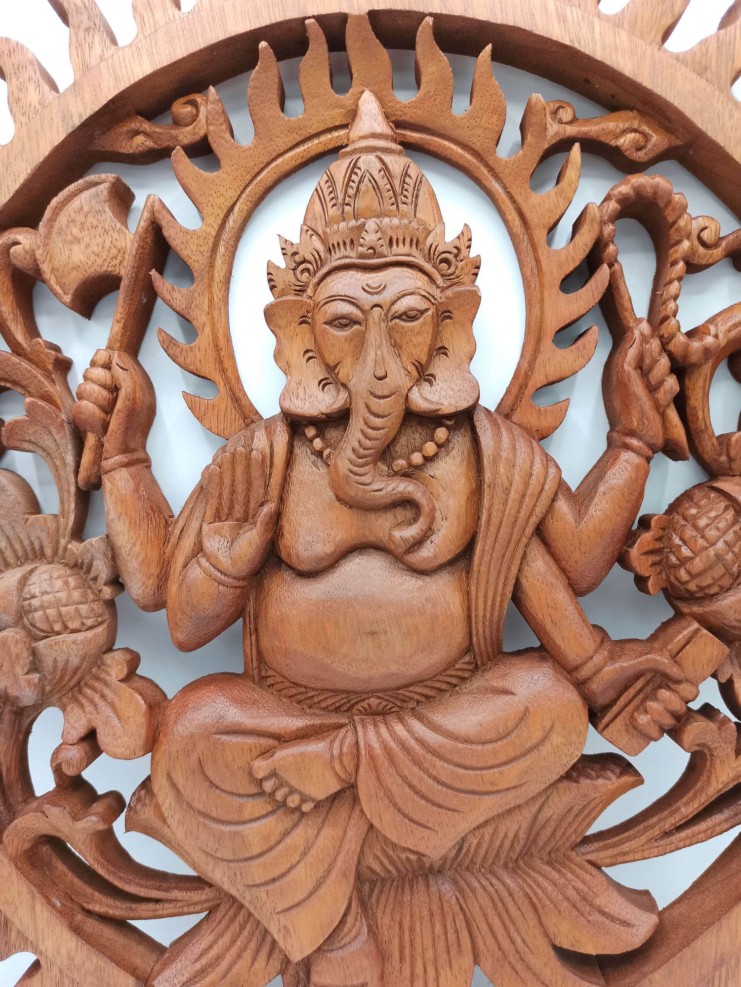 Wooden carving of a deity with intricate details on a white background