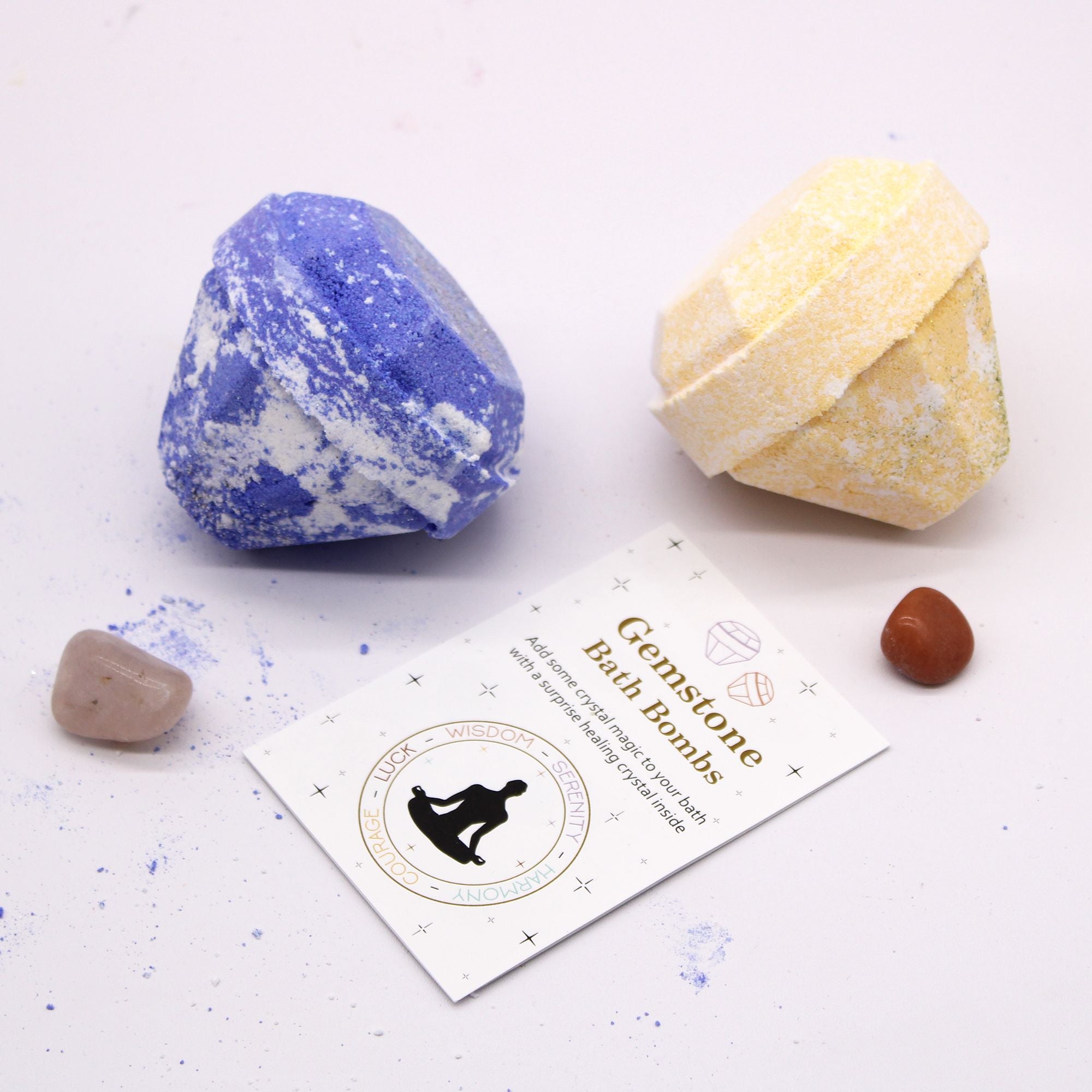 Two gemstone bath bombs, one blue and one yellow, with a branded card on a light background.