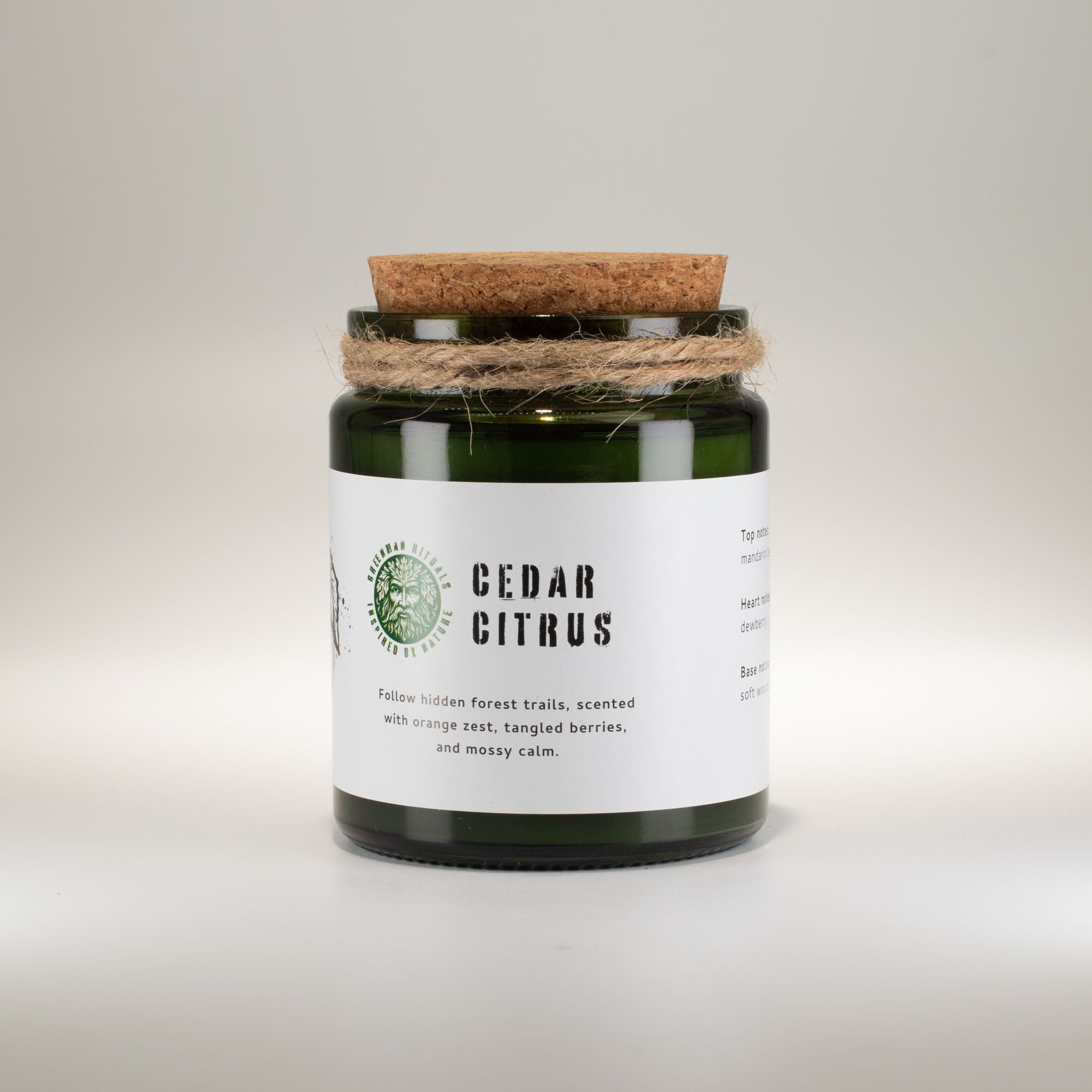 Candle jar with cork lid and white label on a light gray background