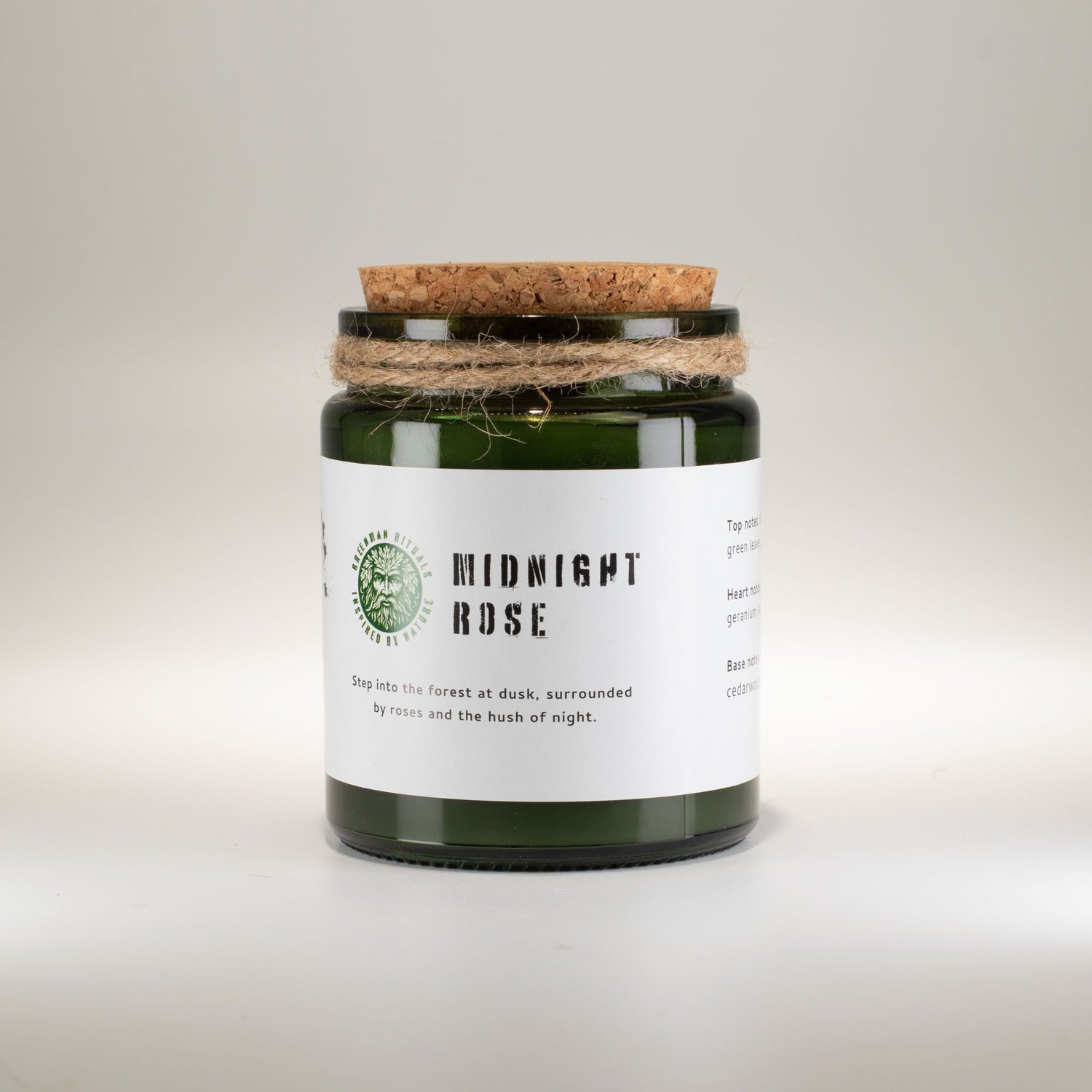 Candle in a green jar with a cork lid on a light gray background