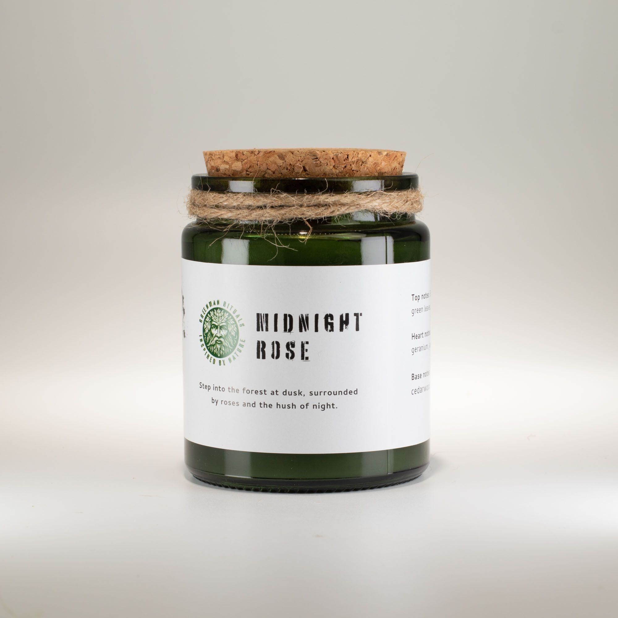 Candle in a green jar with a cork lid on a light gray background