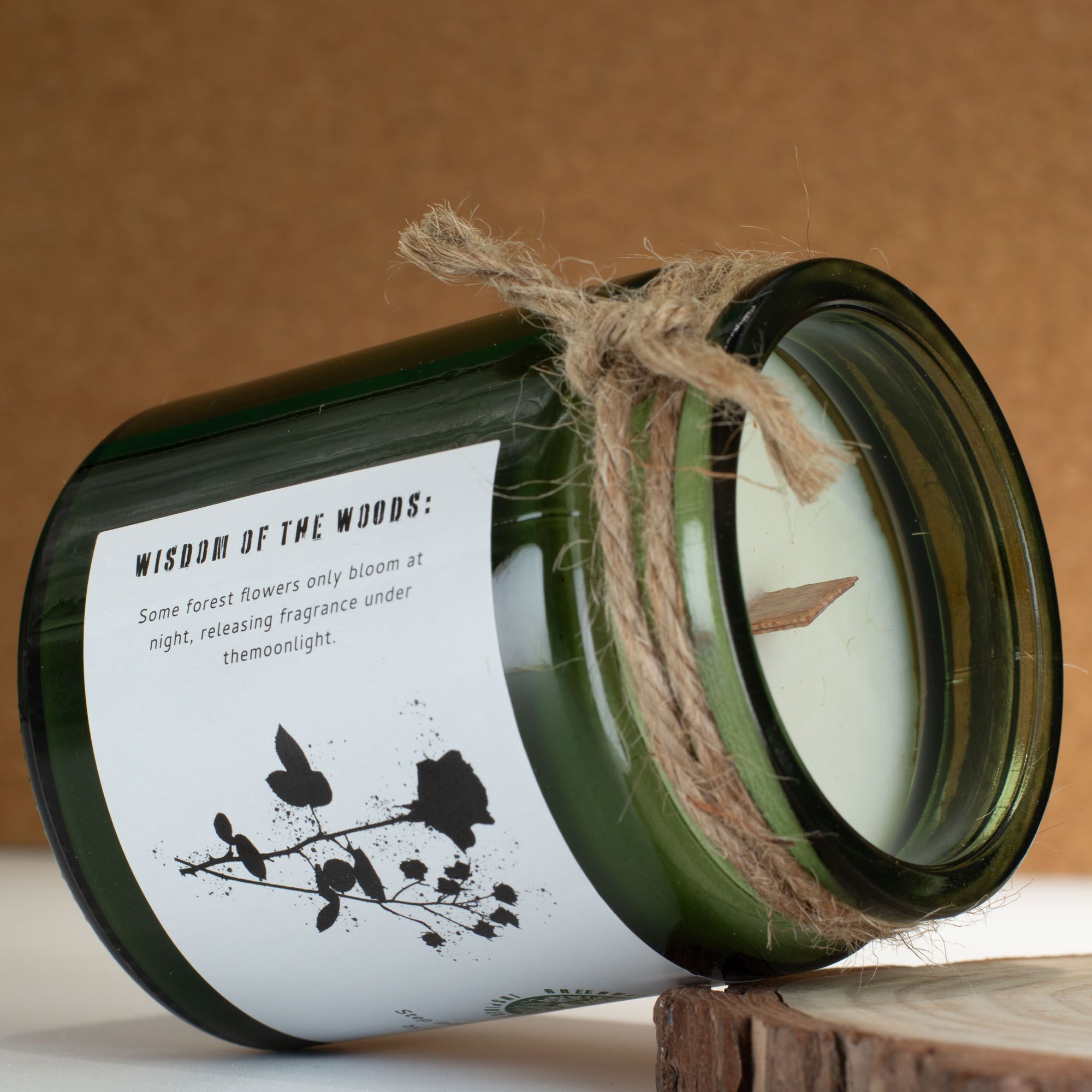 Candle in a green jar with a label and twine on a wooden surface