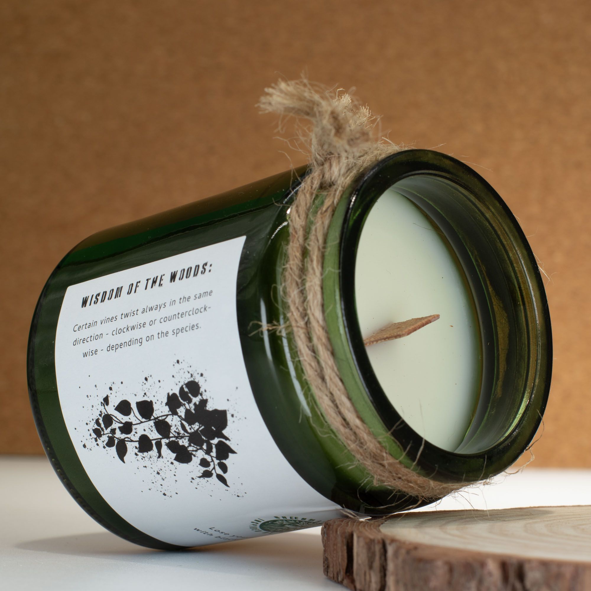 Candle in a green glass jar with a label and twine on a wooden surface
