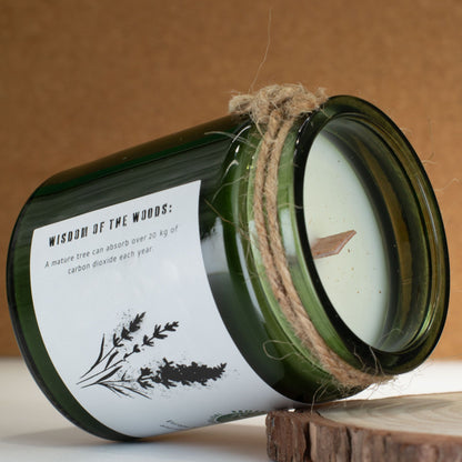 Candle in a green glass jar with a label on a wooden surface