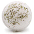 Bath bomb with green herbs on a white background