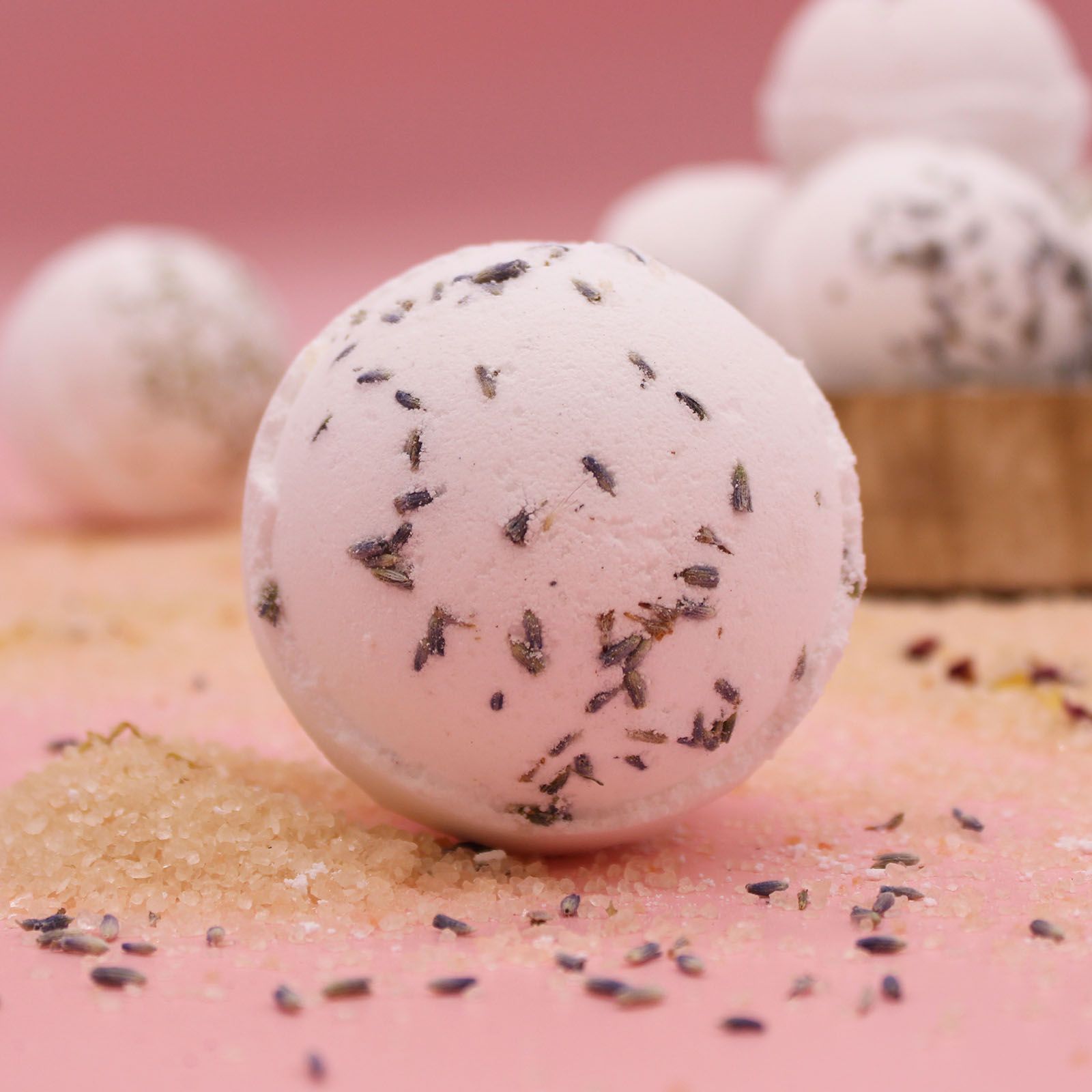 Bath bomb with lavender petals on a pink surface