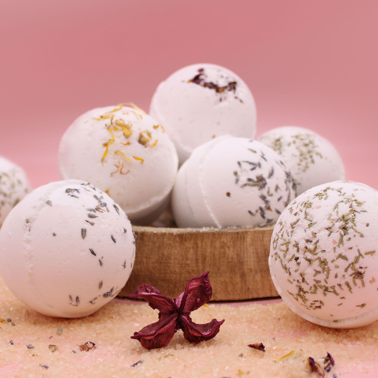 Bath bombs with natural ingredients in a basket on a pink background