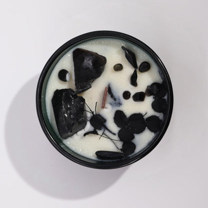 Candle in a dark green container with black obsidian and a wooden wick on a white background