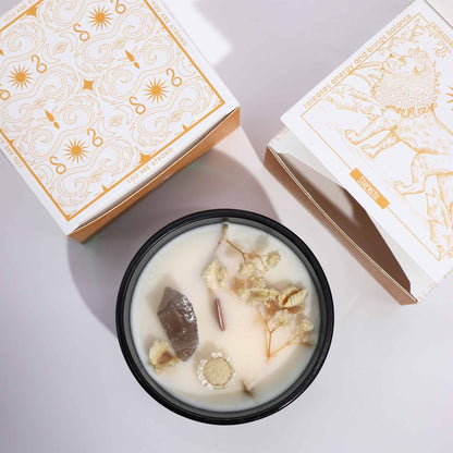 A candle with natural elements in a dark green container on a white background with decorative boxes.