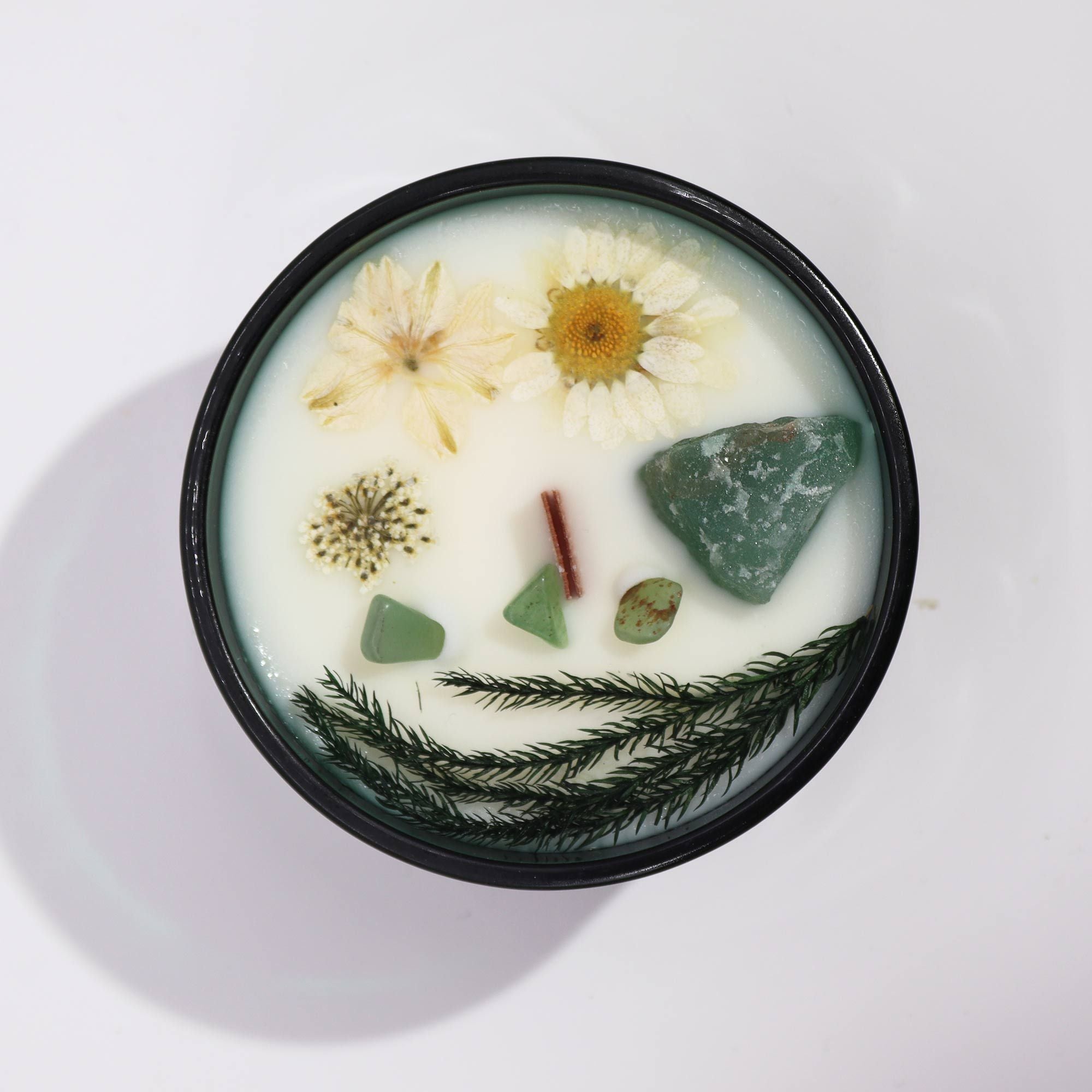 Candle with natural elements like flowers and stones on a white background