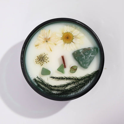 Candle with natural elements like flowers and stones on a white background