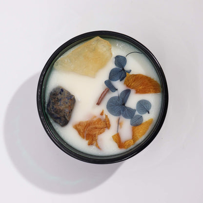 Candle in a black container with floral elements on a white background