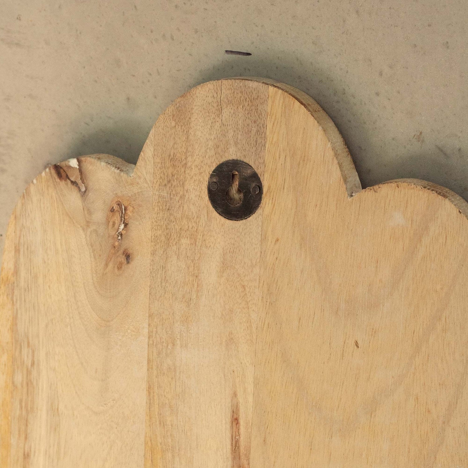 Reverse of a wooden plaque with a decorative edge and metal hanger on a neutral background