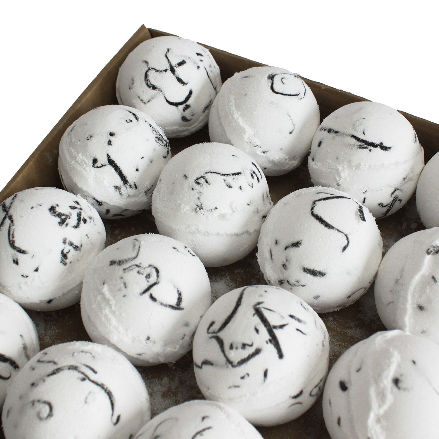 White bath bombs with black marbling and specks on a brown tray