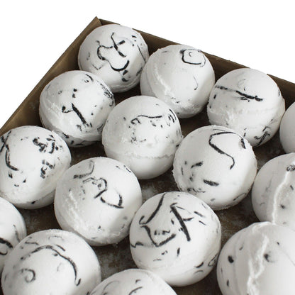 White bath bombs with black marbling and specks on a brown tray