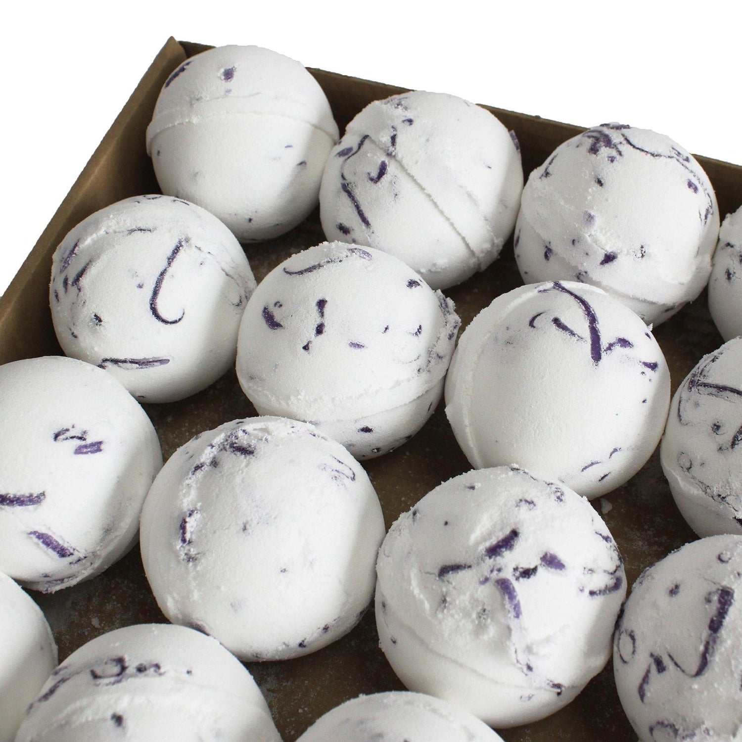 White bath bombs with purple specks in a cardboard box