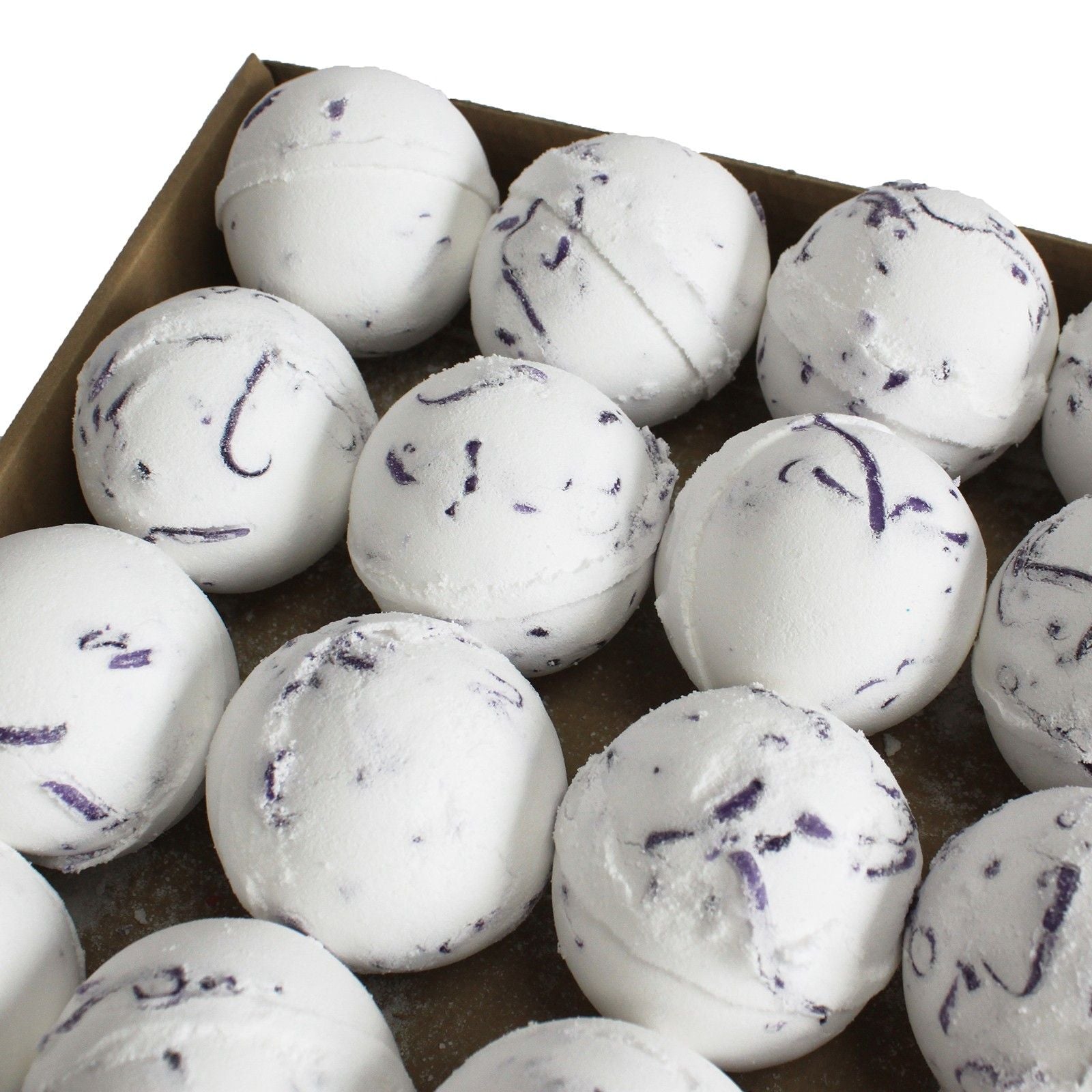 White bath bombs with purple specks in a cardboard box
