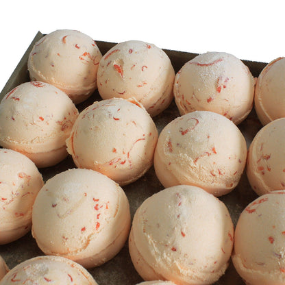 Bath bombs with red specks in a cardboard box on a white background
